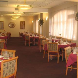 A spacious and well-lit dining room with elegantly arranged tables and chairs.
