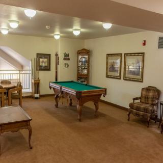A cozy game room featuring a pool table and comfortable seating with decorative wall art.