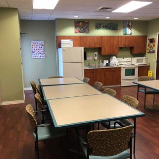 A communal kitchen area featuring tables, chairs, and standard kitchen appliances.
