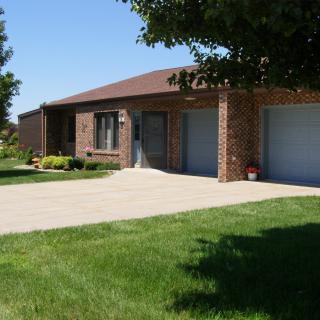 A suburban brick house with a well-maintained lawn and driveway.