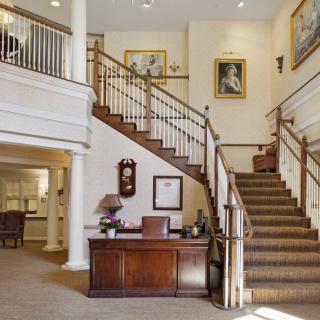 Elegant lobby featuring a grand staircase and a wooden desk.