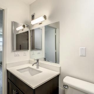 A modern bathroom with a sleek vanity, large mirror, and contemporary lighting.