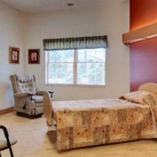 A cozy bedroom with a single bed, comfortable chair, and warm decor.