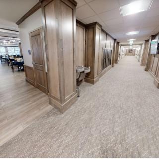 A modern hallway with wood paneling and carpeted floors, featuring overhead lighting.