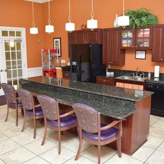 A modern kitchen with an island and bar stools, featuring granite countertops and pendant lighting.