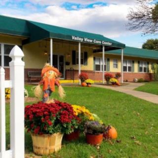 A daycare center decorated with autumn flowers and festive displays outside the building.