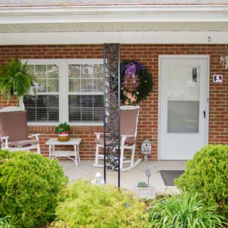 A cozy brick porch with chairs and potted plants.