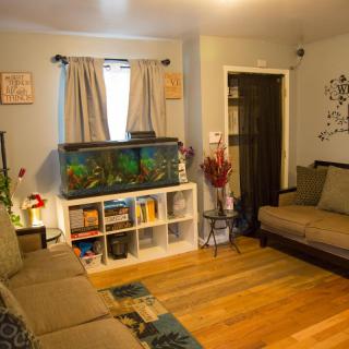 A cozy living room with a fish tank, sofas, and a small bookshelf.