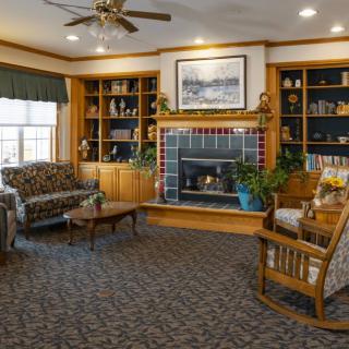 A cozy living room with a fireplace, surrounded by bookshelves and comfortable seating.