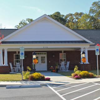 A small building with a porch and autumn decorations, featuring nearby parking spaces.