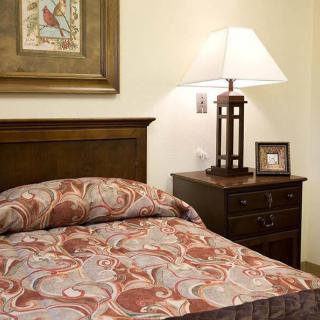 A cozy bedroom with a bed and nightstand featuring a lamp and framed picture.