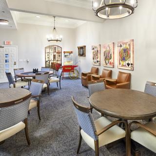 A well-furnished room with round tables, chairs, and decorative artwork on the walls.