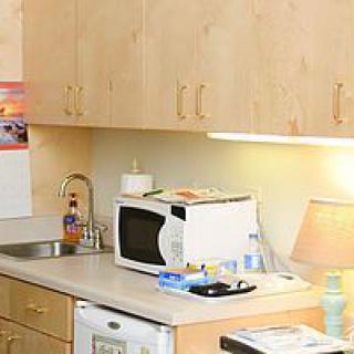A kitchenette with a microwave, sink, and wooden cabinets.