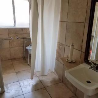 A tiled bathroom with a shower, sink, and mirror.
