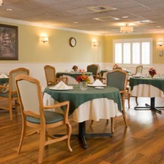 An elegant dining room with neatly arranged tables and chairs, featuring soft lighting and tablecloths.