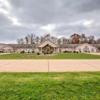 A spacious building surrounded by green grass and a cloudy sky.
