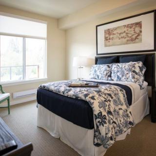 A cozy bedroom with a neatly made bed and large window providing natural light.