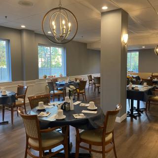 A well-lit restaurant dining area with neatly arranged tables and chairs, complemented by a stylish chandelier.