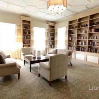 A cozy library with bookshelves lining the walls and a comfortable seating area bathed in natural light.