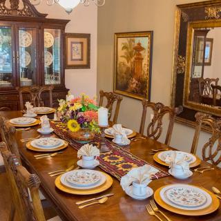 A beautifully set dining table with elegant dinnerware and a floral centerpiece in a classic dining room.