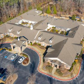 Aerial view of a large building with a surrounding parking lot and trees.