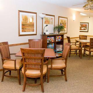 A cozy seating area featuring wooden tables and chairs, adorned with wall art and soft lighting.