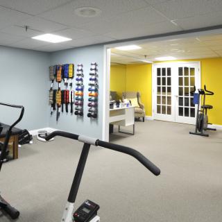 A well-equipped home gym featuring exercise machines and colorful sports bands on the wall.