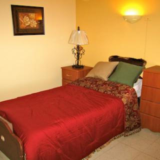 A cozy bedroom featuring a neatly made bed, decorative pillows, and warm lighting.