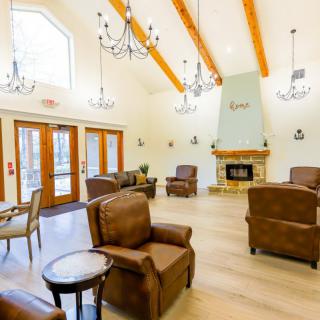 A cozy lounge area with leather chairs, a fireplace, and large windows.