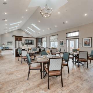 A spacious and elegantly designed dining area with multiple tables and chairs, featuring modern decor and ample natural lighting.