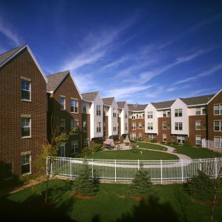 A view of a modern apartment complex with brick buildings and landscaped surroundings under a clear blue sky.