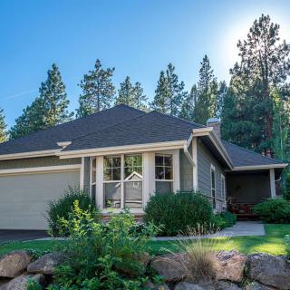 A charming residential house surrounded by lush greenery and tall trees.