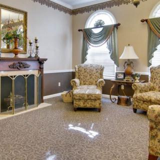 A traditional living room with patterned armchairs, a fireplace, and elegant window drapes.