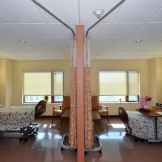 A hospital room with two beds separated by a curtain.