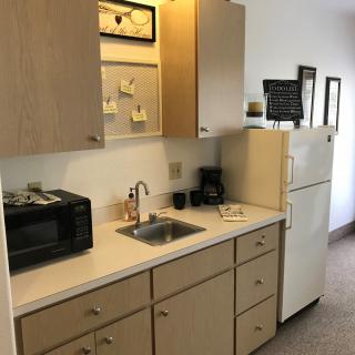 A small kitchen area featuring a microwave, sink, and refrigerator.