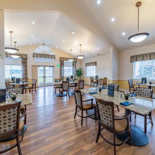 A spacious dining area with elegant tables and chairs, featuring wooden flooring and modern lighting.