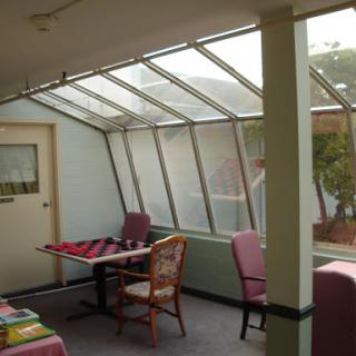 A cozy sunroom with a glass ceiling, featuring tables and chairs for relaxation.