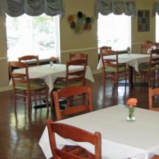 A neatly arranged dining area with tables covered in white tablecloths and decorated with small flower vases.