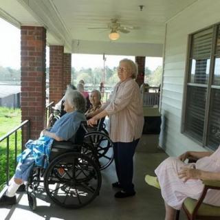 A group of elderly individuals enjoying the outdoors on a porch.