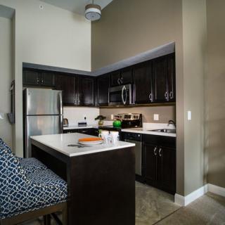 A modern kitchen with dark cabinets and stainless steel appliances.