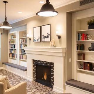 A cozy living room with a fireplace, modern lighting, and built-in bookshelves.