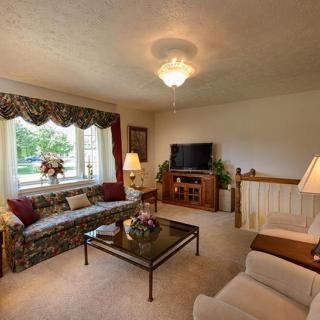 Cozy living room with a sofa, coffee table, and television, featuring elegant decor and large windows.