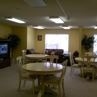 A cozy living room with round tables, chairs, sofas, and a television.