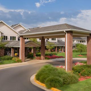 Entrance of a residential building with landscaped surroundings and a covered driveway.