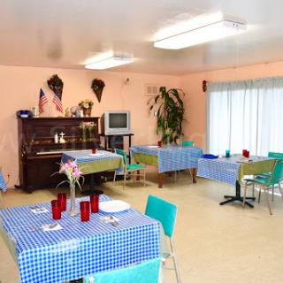 A cozy dining area featuring blue checkered tablecloths and a piano, creating a welcoming atmosphere.