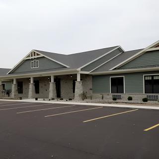 A modern commercial building with an empty parking lot under an overcast sky.