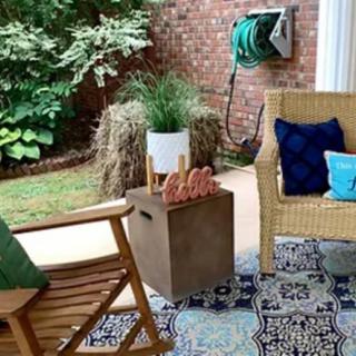 A cozy patio setup with outdoor seating, colorful cushions, and lush greenery.