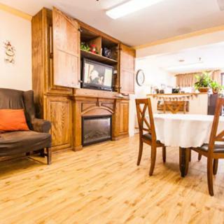 A cozy living and dining area with wooden flooring, a TV in a cabinet, and a round table with chairs.