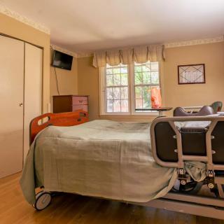 A hospital room with a bed, television, and large window.