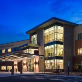 A modern building illuminated at night with large glass windows.